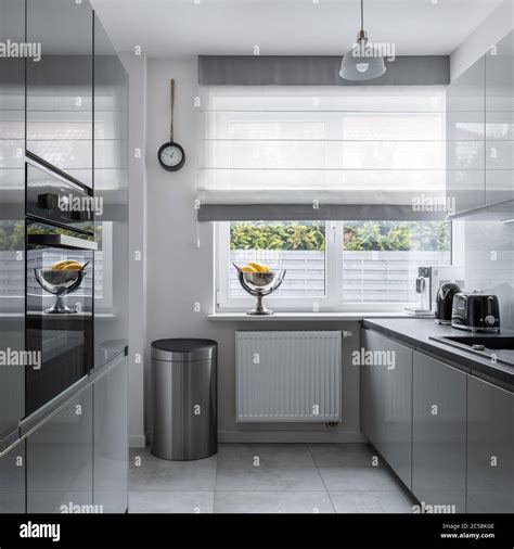 Modern, narrow kitchen with window and gray furniture Stock Photo - Alamy