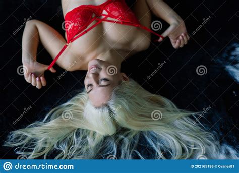 Fashion Model With Blond Hair Posing In Bedroom Wearing Red Lingerie