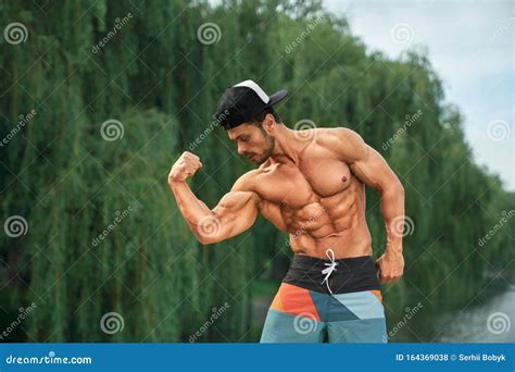Bodybuilder With Naked Torso Showing Muscles Outdoors Stock Photo