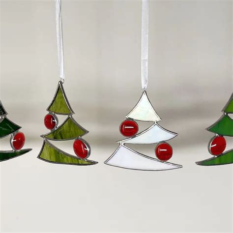 Three Christmas Tree Ornaments Hanging From Strings