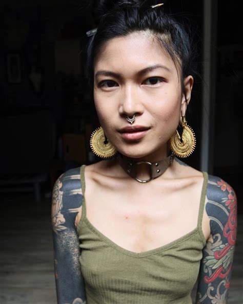 A Woman With Tattoos And Piercings On Her Chest Posing For The Camera