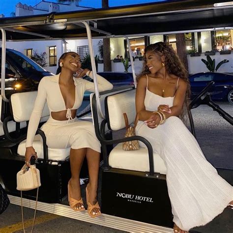 Two Women In White Dresses Are Sitting On A Golf Cart And One Is