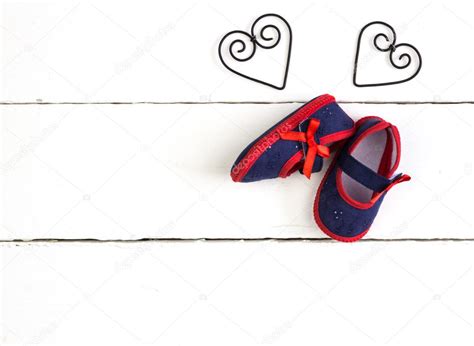 Overhead photo of pair of navy and red baby booties, heart metal ...