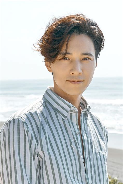 A Man Standing On Top Of A Beach Next To The Ocean With His Hair