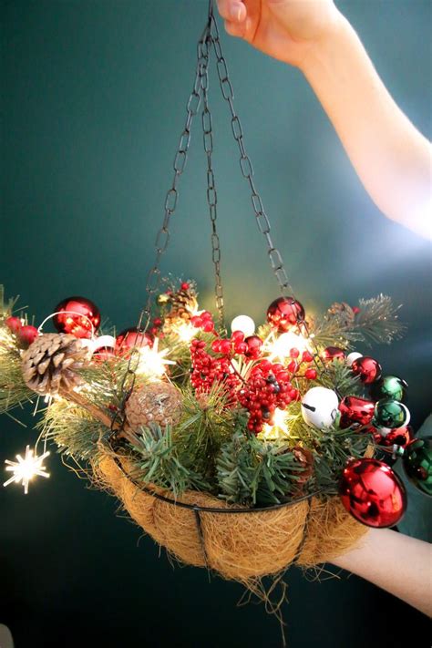 A Person Holding A Basket With Christmas Decorations On It And Lights Hanging From The Ceiling