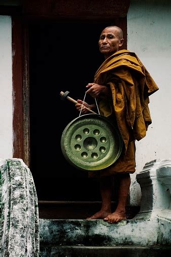 Buddhist Monk With A Gong In Front Of The Entrance Of His Monastery