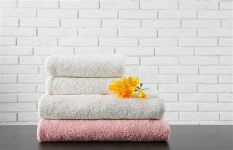 Stack of Folded Soft Towels with Flower on Table Near Brick Wall. Stock ...