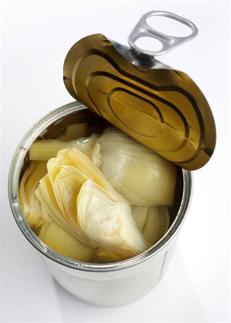 Peeled Artichokes Sit In A Container With Tongs On The Top And Bottom