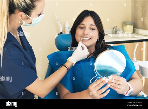 Female Dentist Checking On Female Patient Teeth Color Using Tooth