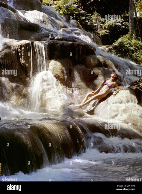 Woman In Bikini Reclining On Rocks Amidst Waterfall Stock Photo Alamy