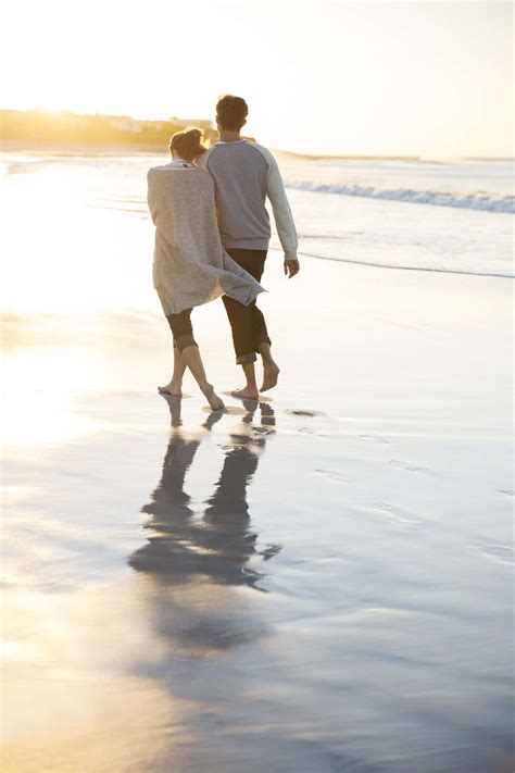 Download Couple At Beach Walking On Wet Sand During Sunset Picture