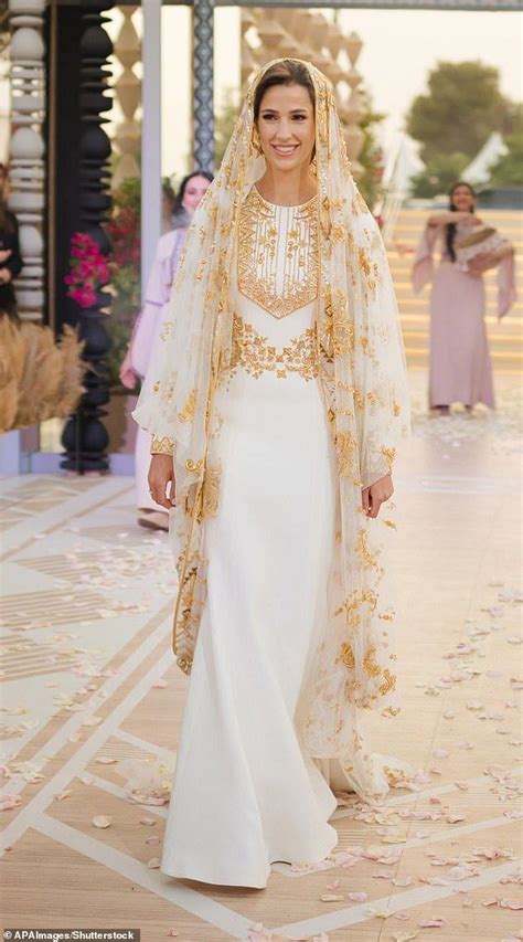 A Woman In A White Dress And Veil Walking Down A Runway With Other