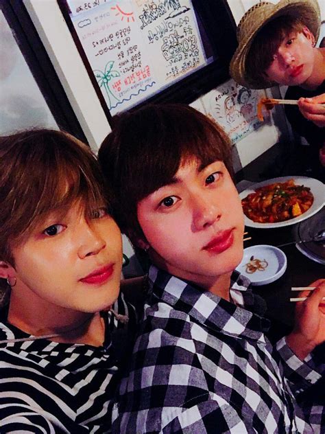 Three People Sitting At A Table With Food And Chopsticks In Front Of Them