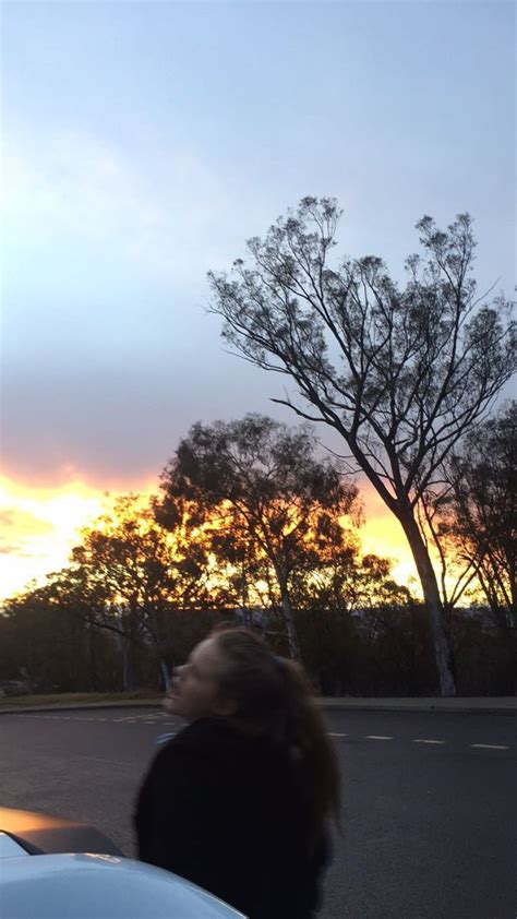 A Woman Is Sitting In The Back Of A Car Watching The Sun Go Down Behind Her