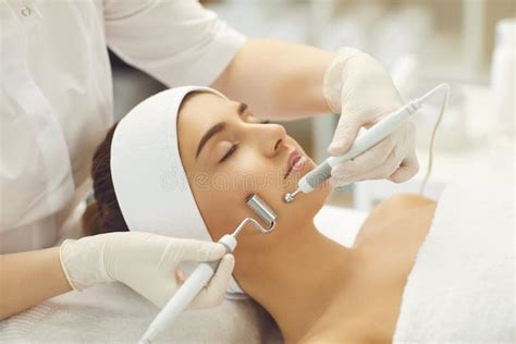 Woman Receiving Facial Microcurrent Treatment From Therapist In Beauty