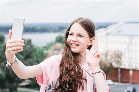 Premium Photo A Cheerful Girl In Glasses Takes A Selfie On A Smartphone Content For Social