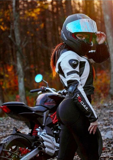 A Woman In Black And White Riding Gear Next To A Motorbike Wearing A Helmet