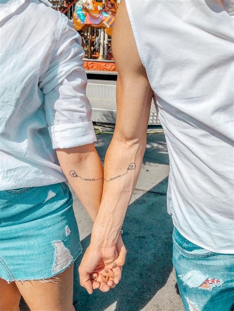 Two People Holding Hands While Standing Next To Each Other In Front Of