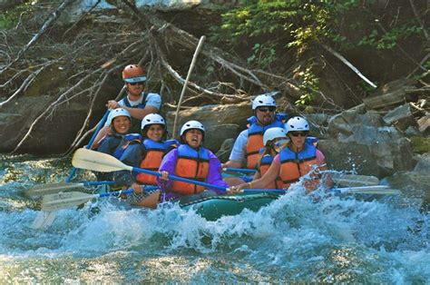 A Group Of People Riding On The Back Of A White Water Raft Down A River