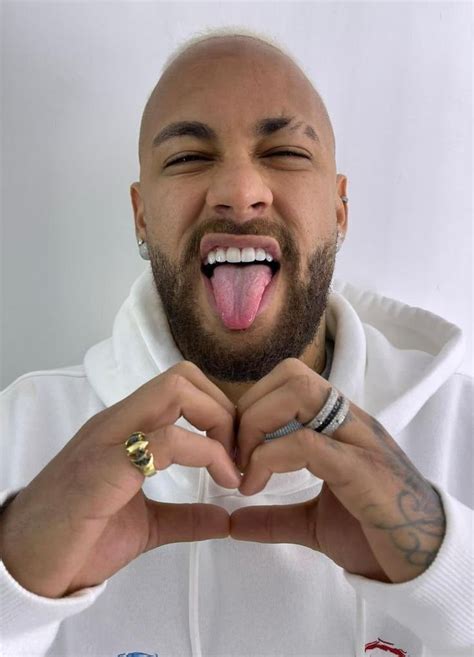 A Man Making A Heart Shape With His Hands While Wearing A White Shirt