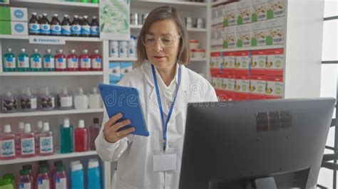Mature Woman Pharmacist Using Tablet In A Modern Drugstore Stock Photo Image Of Drugstore