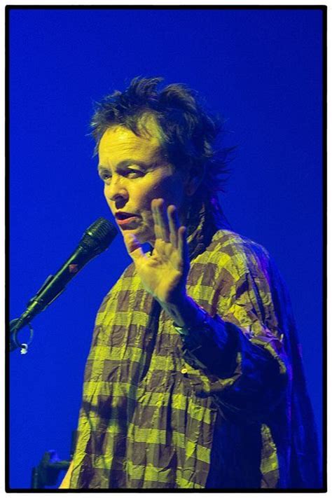 A Man Standing In Front Of A Microphone With His Hand Up To His Face