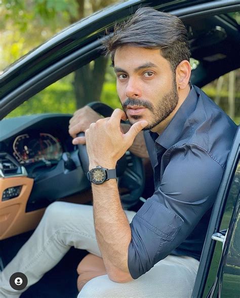 A Man Sitting In The Driver S Seat Of A Car With His Hand On His Chin