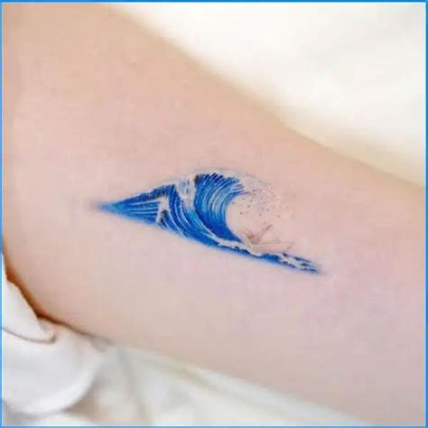 A Person With A Blue Wave Tattoo On Their Arm