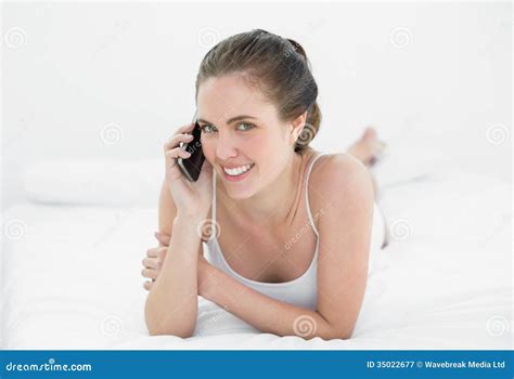 Portrait Of A Smiling Woman Using Mobile Phone In Bed Stock Image