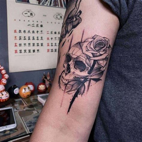 A Skull And Rose Tattoo On The Arm