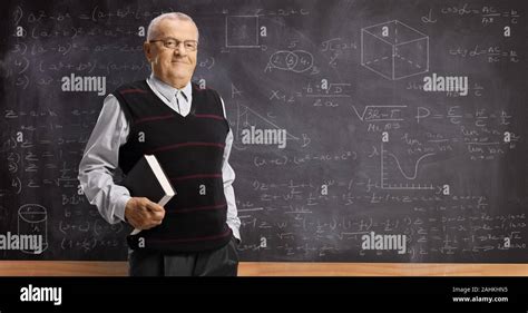 Elderly Professor With A Book Standing In Front Of A Blackboard With