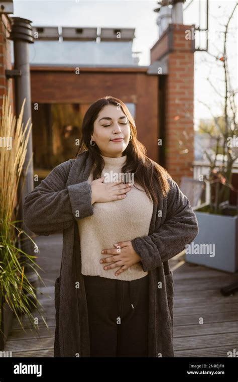 Woman With Eyes Closed Practicing Breathing Exercise While Standing At