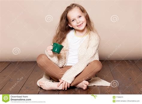 La Petite Fille S Assied Avec Une Tasse Sur Le Plancher Image Stock