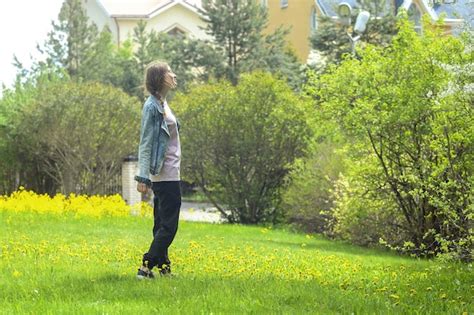 Une Belle Femme Blonde Se Prom Ne Le Long D Une Pelouse Vert Vif Avec Des Fleurs Jaunes Photo