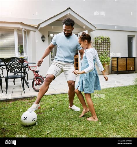 Lazos de padre e hija jugando con el balón de fútbol en el patio