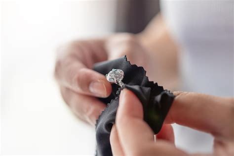 Premium Photo | Jeweller cleaning jewelry diamond ring with fabric cloth