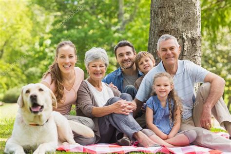 Familia Extendida Con Su Perro Sentado En El Parque Foto De Stock