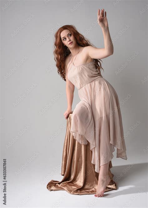 Full Length Portrait Of Beautiful Female Model With Long Brunette Hair Wearing A Creamy Pink