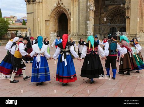 A folk dance group in traditional costumes dancing to bagpipe music in front of Oviedo cathedral ...