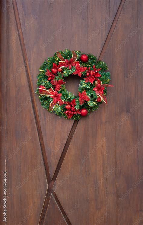 Vertical photo. Round green Christmas wreath on a wooden door. New Year ...