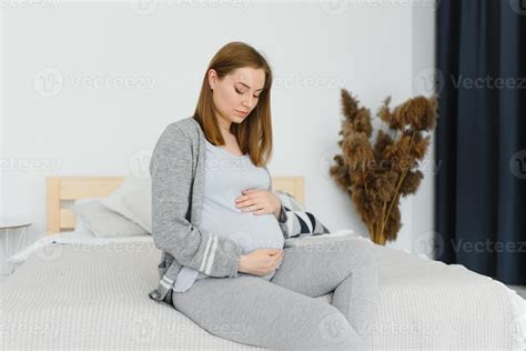 Beautiful Pregnant Woman Holds Hands On Belly In Bedroom At Home Young