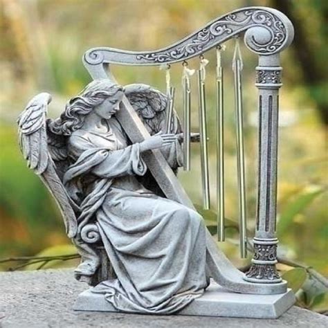 An Angel Figurine Sitting On Top Of A Rock Next To A Musical Instrument