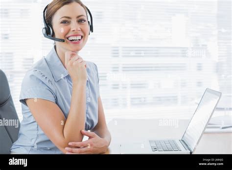 Laughing Call Centre Agent Wearing Headset At Her Desk With Laptop In