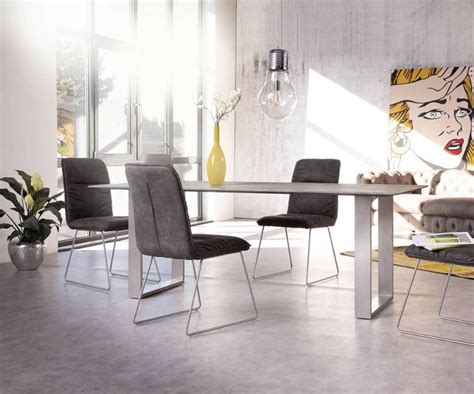 A Modern Dining Table With Four Chairs And A Painting On The Wall In