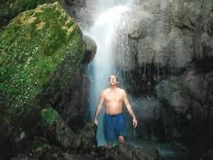 A Man Standing In Front Of A Waterfall