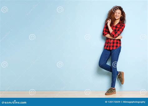 Full Body Happy Woman with Curly Hair Leaning Against Blue Background ...