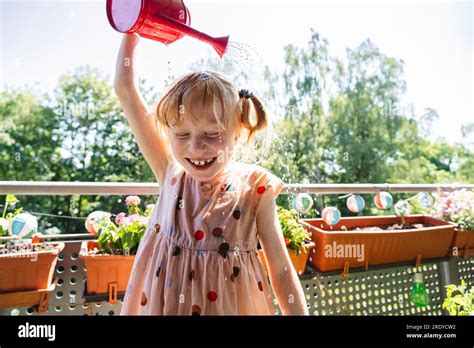 Happy Girl Pouring Water On Herself In Balcony Stock Photo Alamy