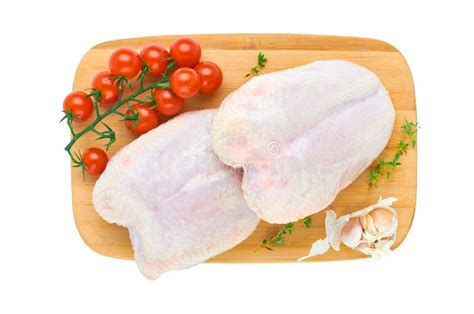 Two Fresh Chicken Breasts On A Cutting Board With Vegetables And Herbs