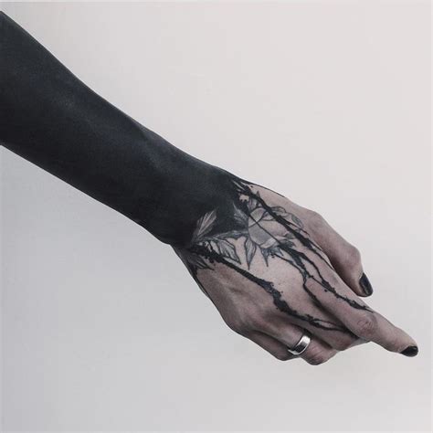 A Person S Arm And Hand With Black Ink On It Holding Something In The Air