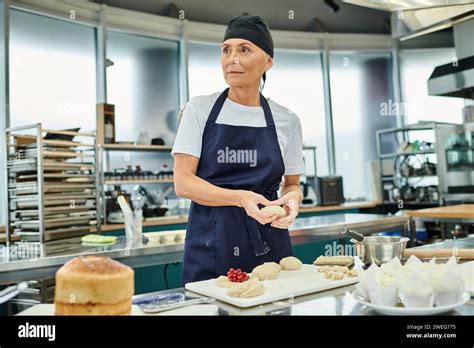 Good Looking Mature Female Chef In Apron Working With Dough And Looking